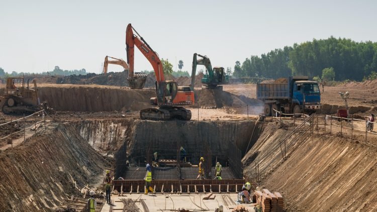 A close shot of heavy machines and construction workers working on a building